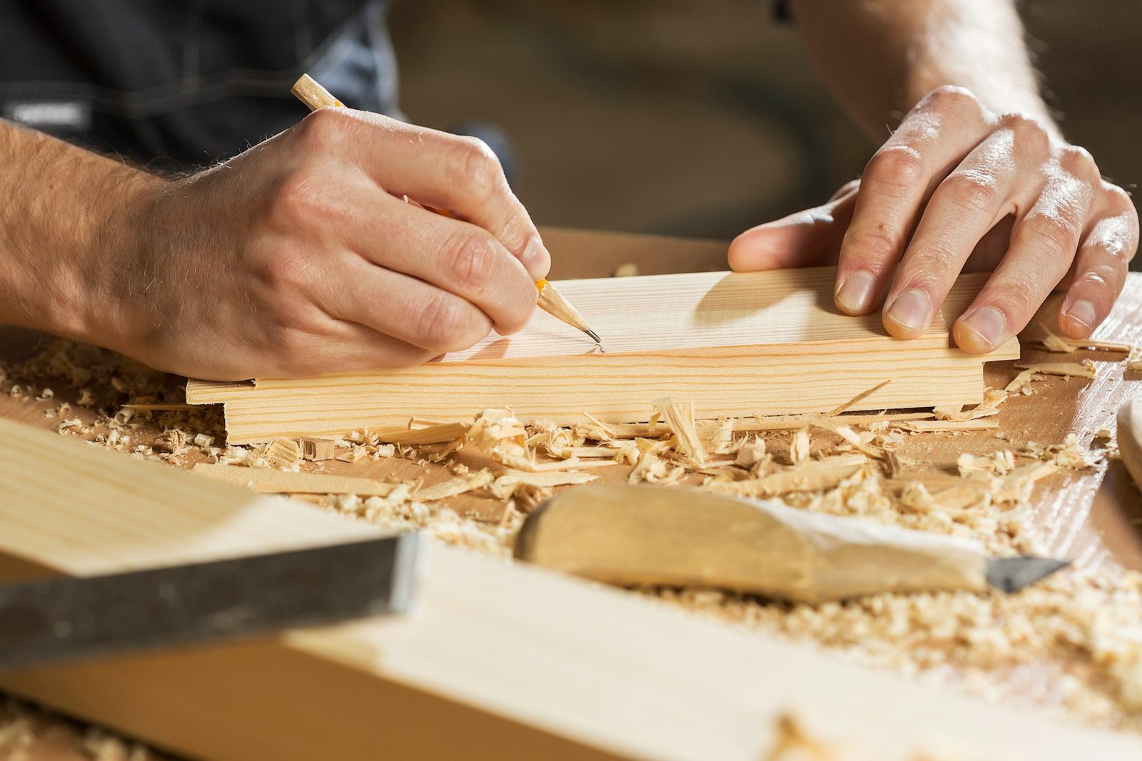 Carpenter marking a precise cut line on timber with a pencil