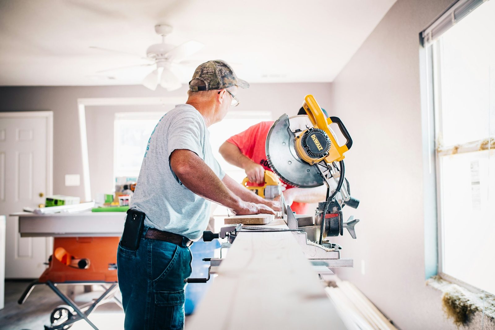 Carpenter cutting timber with a mitre saw inside a home under renovation