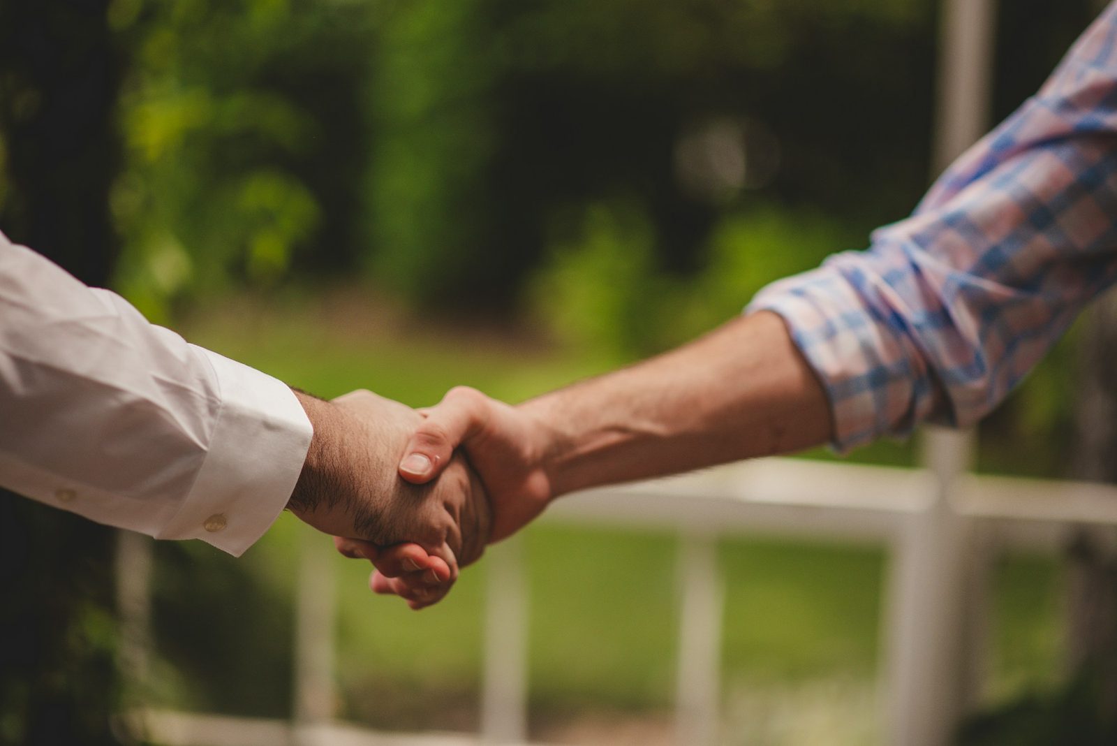 Builder and homeowner shaking hands outdoors after finishing a job