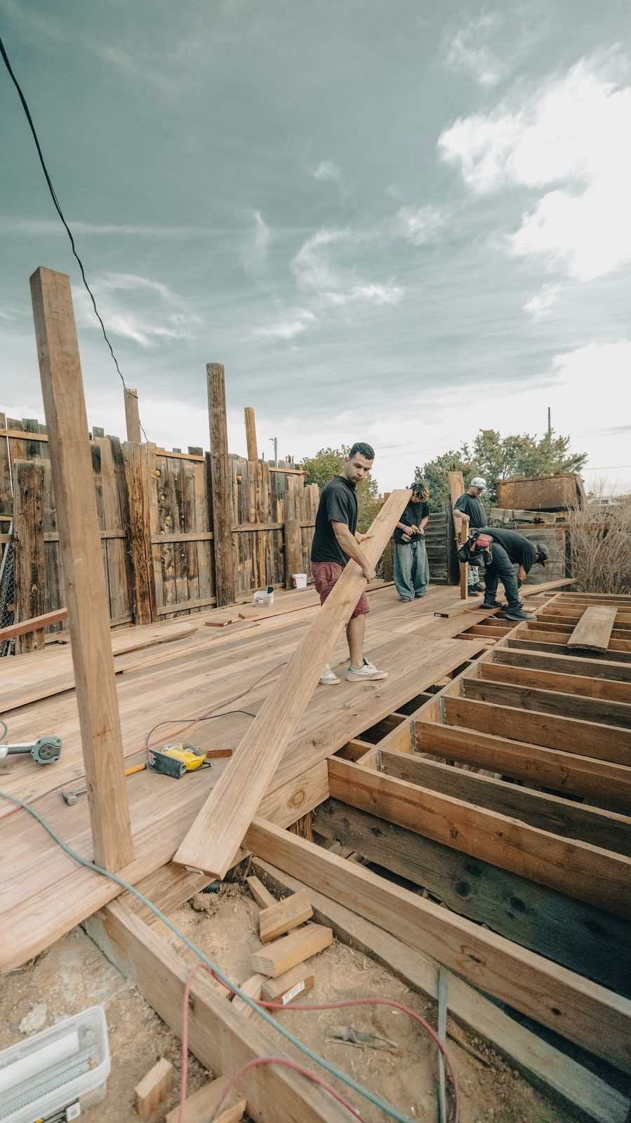 Builders constructing a hardwood timber deck frame outdoors