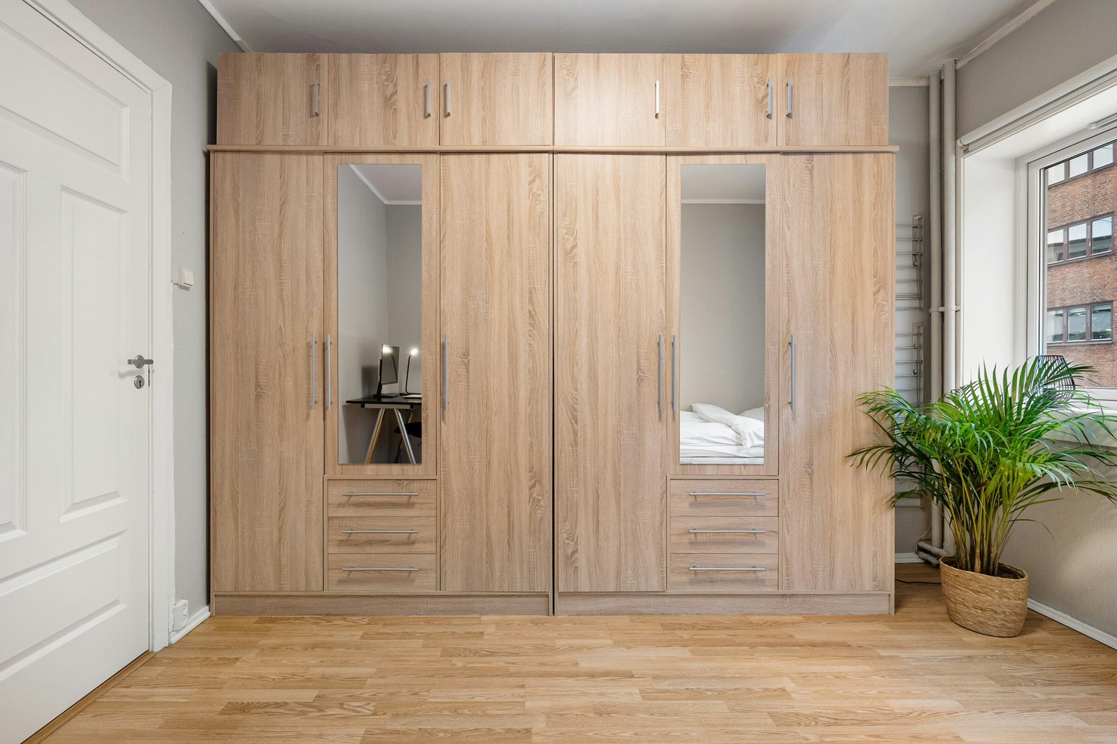 Floor-to-ceiling built-in timber wardrobe with mirrored doors in a bedroom