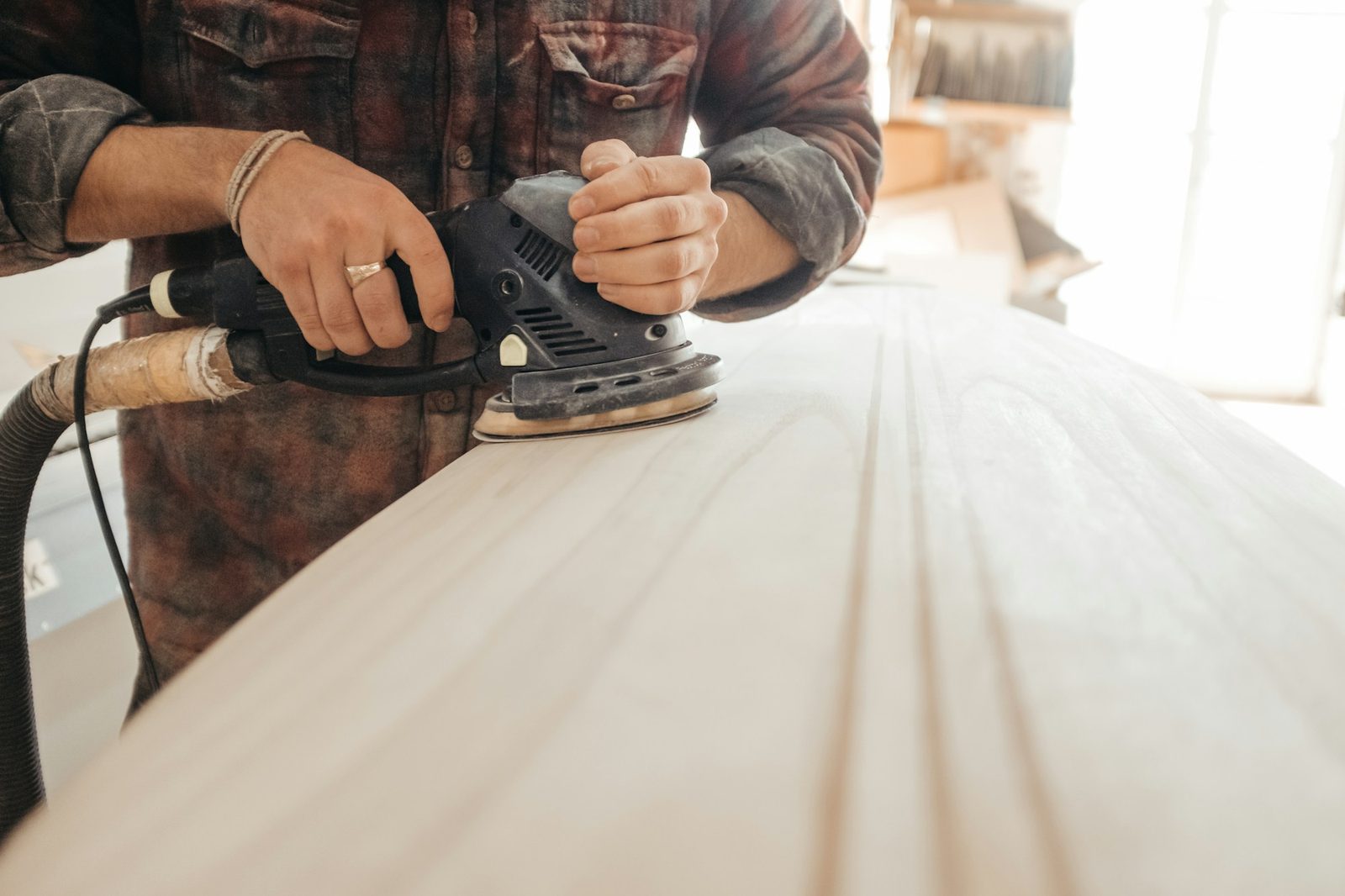 Carpenter sanding a timber board smooth during a repair